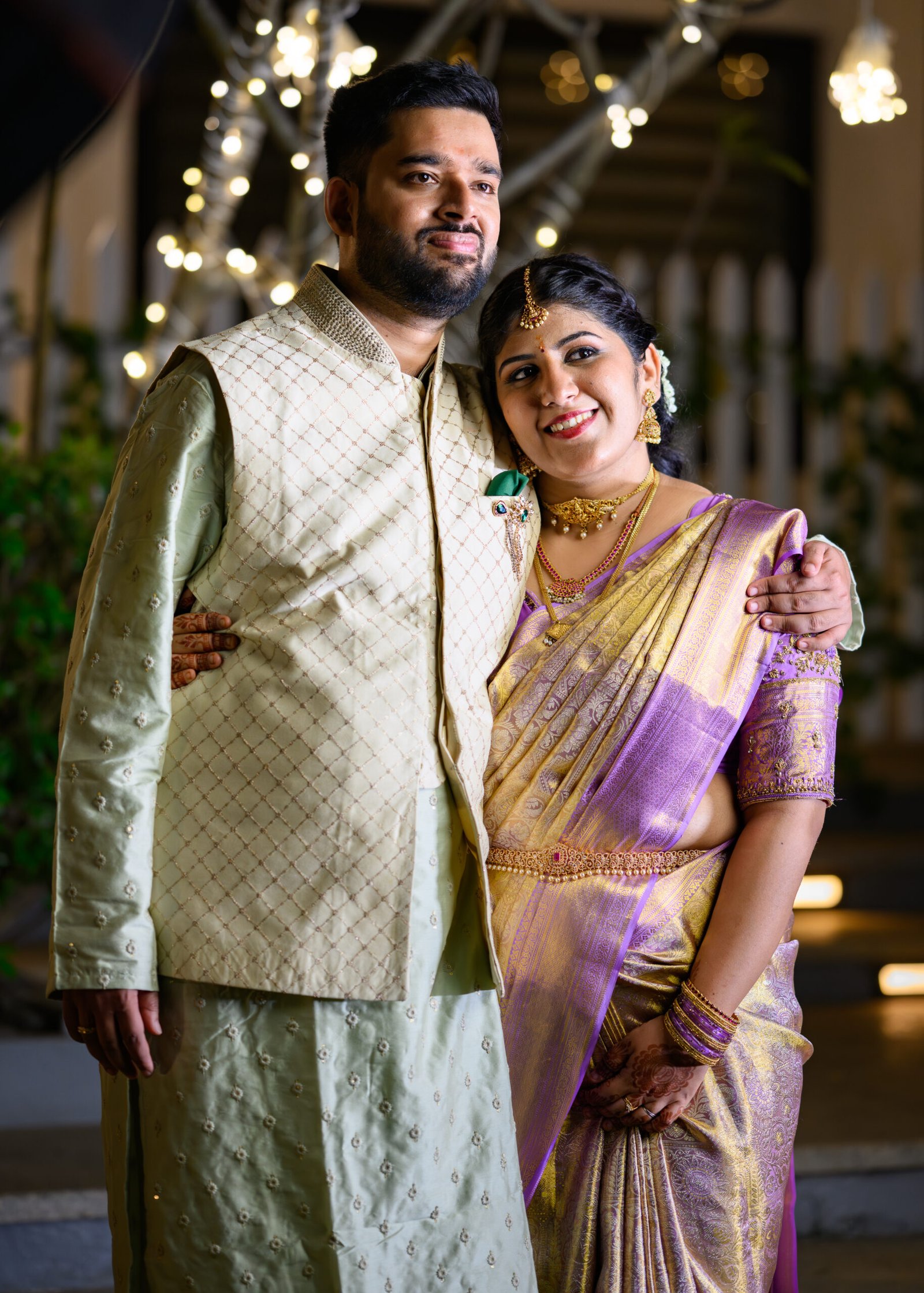 Engaged couple standing together beneath warm lights